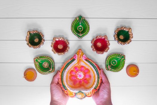 Happy Diwali - Clay Diya lamps lit during Dipavali, Hindu festival of lights celebration. Colorful traditional oil lamp diya on white wooden background