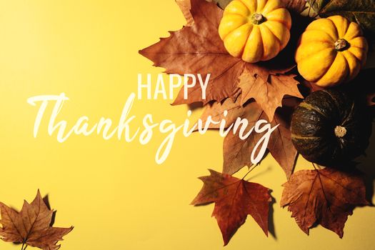Happy Thanksgiving Day with maple leaves and pumpkin on yellow background
