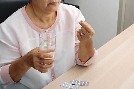 headache old women hand hold medicine with a glass of water, feeling stress, migraine, health problem concept