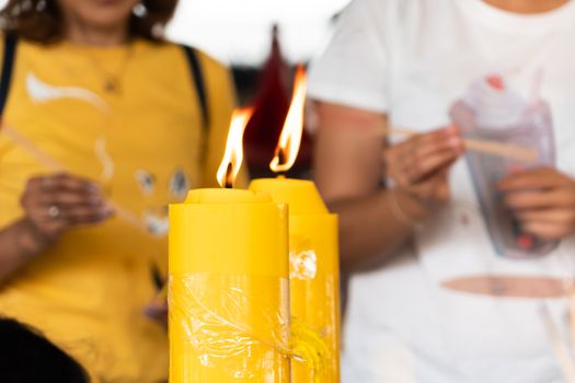 Lighting the candle pray to Buddha, big candle and Flame lit by the big candle's fire.