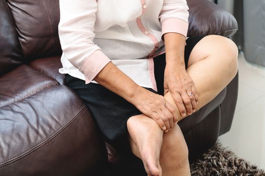 leg cramp, senior woman suffering from leg cramp pain at home, health problem concept