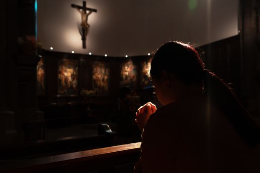 depressed women sitting in the low light church and praying to jesus on the cross, International Human Rights day concept