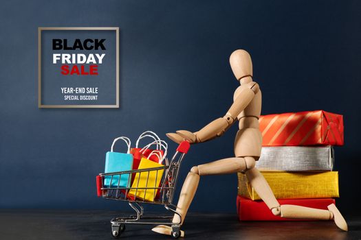 Black Friday sale, wooden doll running with shopping cart and shopping bag