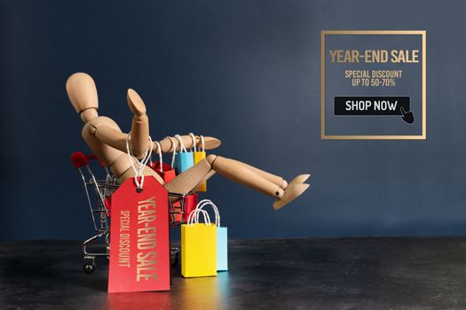 Year-End sale, wooden doll sitting on shopping cart with shopping bag