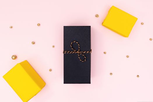 Christmas Gift box, black and yellow present box on pink background. Christmas, winter, new year concept. Flat lay, top view, copy space