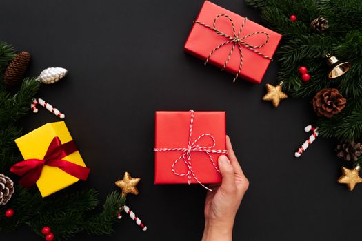 Hand hold christmas gift box with pine tree and xmas decoration on black background