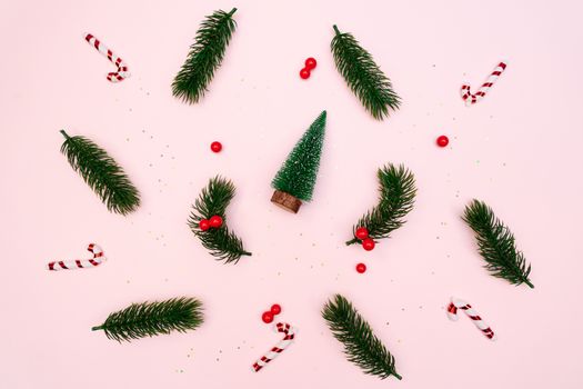Christmas pine tree with xmas decoration on pink background, flat lay composition