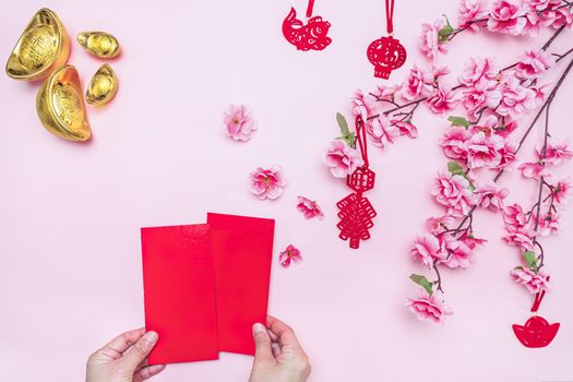 Flat lay Chinese lunar new year hand offering red envelope on pink background, Translation of text appear in image: Prosperity, rich and healthy.