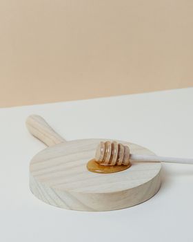 Honey dipper on a wooden tray. Copy space.