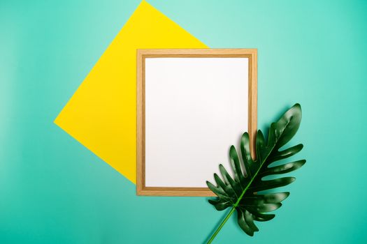 Summer composition. Tropical palm leaves, yellow paper blank, photo frame on pastel green background.