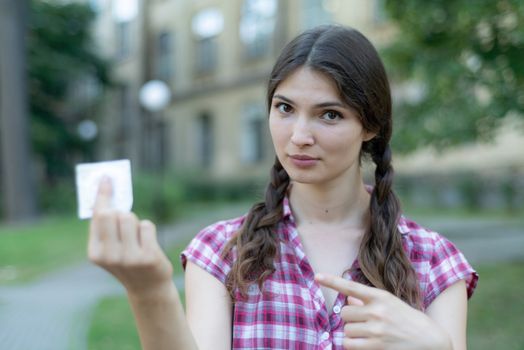 Young girl holding a condom. Protected sex