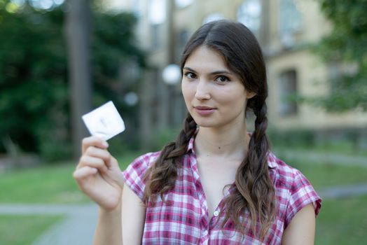 Young girl holding a condom. Protected sex