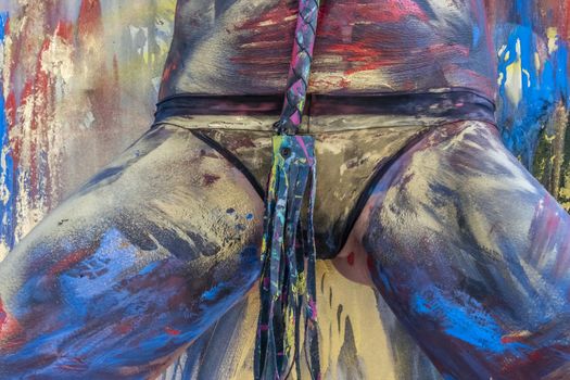 A naked woman is painted with colorful paint in a home environment