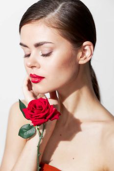 Girl with bare shoulders Eyes closed with a rose in her hands body care light background