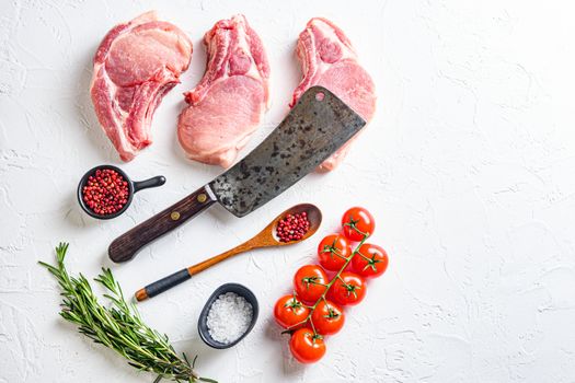 Set for bio grilling butcher cleaver over organic bio Raw pork chops , baking or frying, textured white background. horizontal space for text