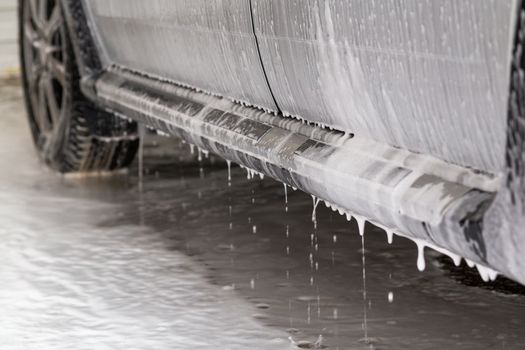 close-up view of silver car step at carwash with soap sud smudges and drops.