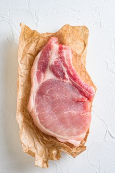 Raw organic pork chop steak top wiev on white textured background top view vertical.