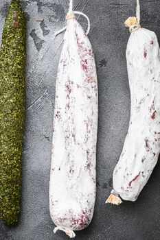 Spanish dry salami from a rack at market on grey background, topview.