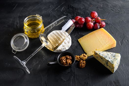 White sauvignon wine Cheese Camembert Fresh figs with grapes honey. Snack on a black background. Side view.