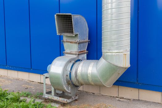 industrial grade air extraction duct with electrical motor on blue wall.