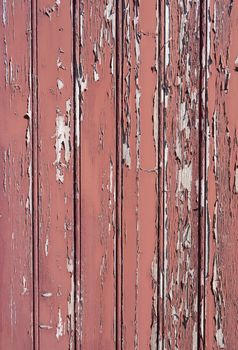 vertical planks with peeling red brown paint in harsh sunlight