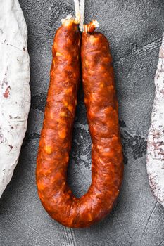 Spanish dry salami from a rack at market on grey textured background.