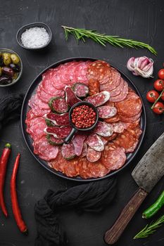Cured meat platter of traditional spanish tapas. Chorizo, salchichon, longaniza and fuet on black textured background, topview.