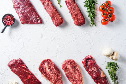 Set of different alternative types of raw beef steaks,on a white stone background top view concept space for text.