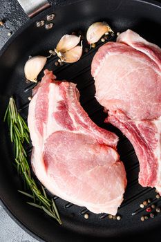 Porco Iberico French Racks in frying pan with herbs, spices close up grey background vertical.