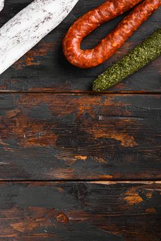 Spanish salami, fuet and chorizo sausages on old wooden table, topview with space for text.
