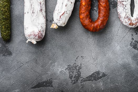 Spanish dry salami from a rack at market on grey textured background, top view with copy space.
