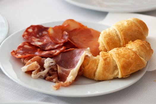 chopped bacon and croissants on a white plate.