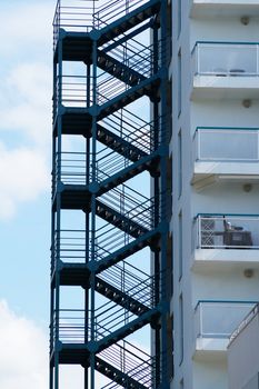 metal fire escape on the wall of a residential building against the background of the sky.