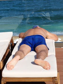 a man sunbathes on a sun lounger on a sun terrace overlooking the sea.