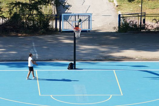 Varna, Bulgaria - August, 22, 2020: young man training with a ball on an outdoor basketball court, view from above