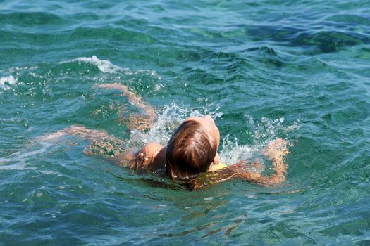 tired teenage girl swims on her back in the sea.