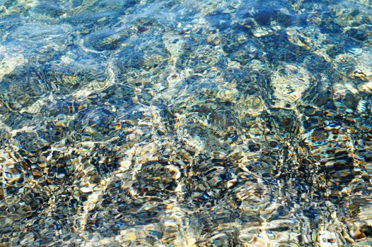 sunlight reflects in clear sea water in shallow water close up