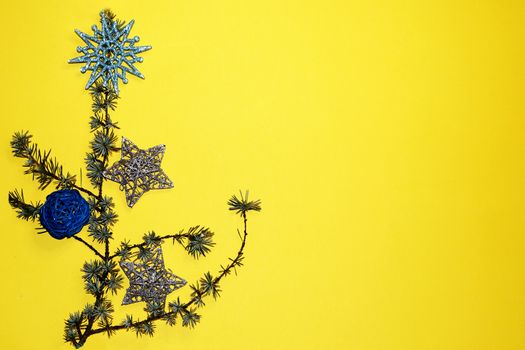 coniferous branches and Christmas tree decorations on a New Year's yellow background, copy space.