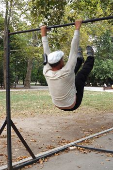 man is engaged on a horizontal bar in the park.