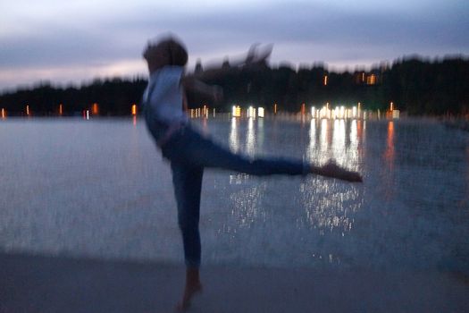 blurred photo, barefoot teenage girl dancing ballet on an empty pier in the evening.