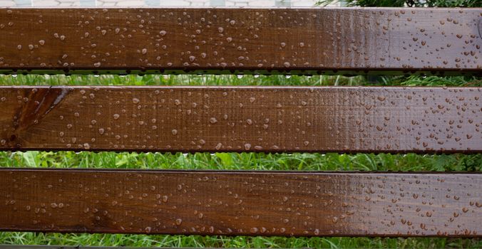 Drops of water on wooden bench after the rain, natural weather background.