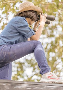 Close up Young asian woman short hair wear hat and hold binocular in grass field countryside Thailand