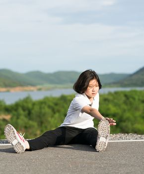 Woman runner doing exercises and warm up preparing for jogging outdoor