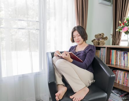 Close up beautiful young asian woman short hair read a book in living room at home