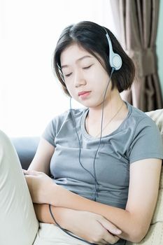 Close up young asian woman short hair listening music from mobile phone on the couch