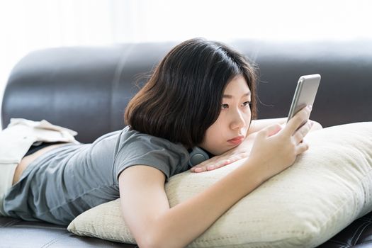 Close up young asian woman short hair listening music from mobile phone on the couch