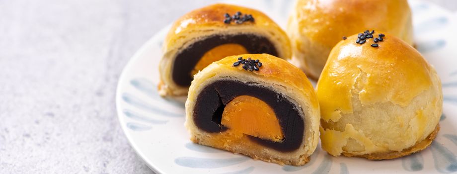 Tasty baked egg yolk pastry moon cake for Mid-Autumn Festival on bright cement table background. Chinese traditional food concept, close up, copy space.