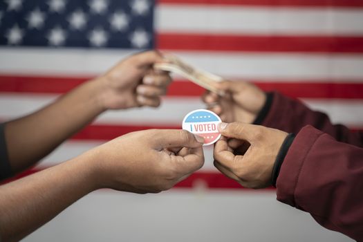 concept of buying votes in US election showing by exchanging I voted sticker with money on US flag as background