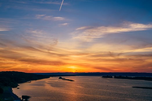 Summer sunset on river shore with orange sky