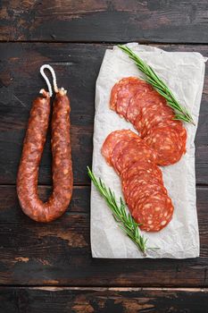 Chorizo, spanish traditional sausage cut to slices on dark wooden background.